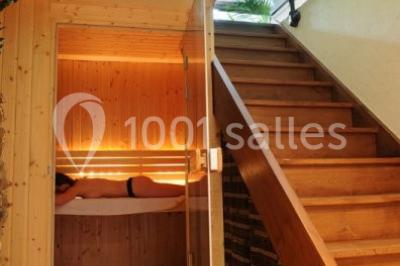 Table en bois décorée pour un repas festif, avec bougies, fleurs et vaisselle, dans une salle aux murs en pierre.