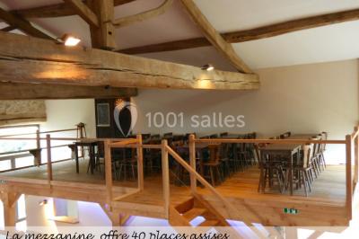Table en bois décorée pour un repas festif, avec bougies, fleurs et vaisselle, dans une salle aux murs en pierre.