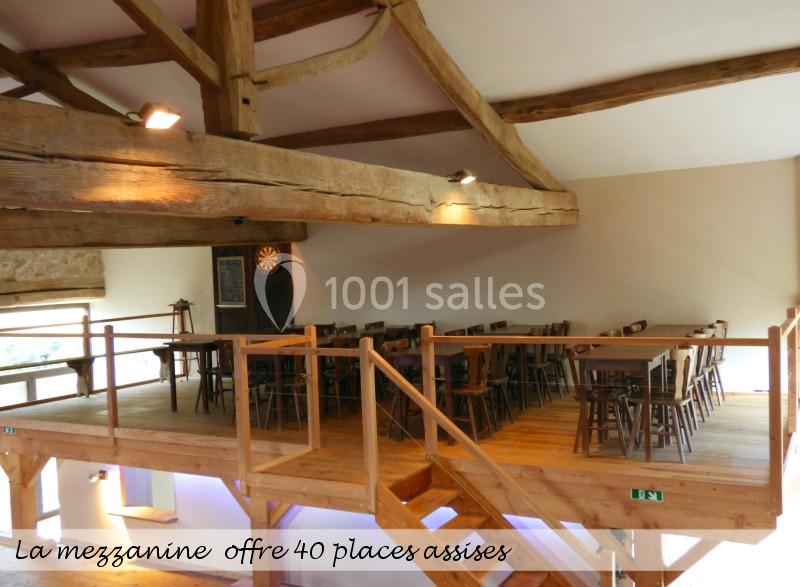 Mezzanine en bois avec tables et chaises, éclairée par des spots, offrant un espace convivial pour 40 personnes assises.