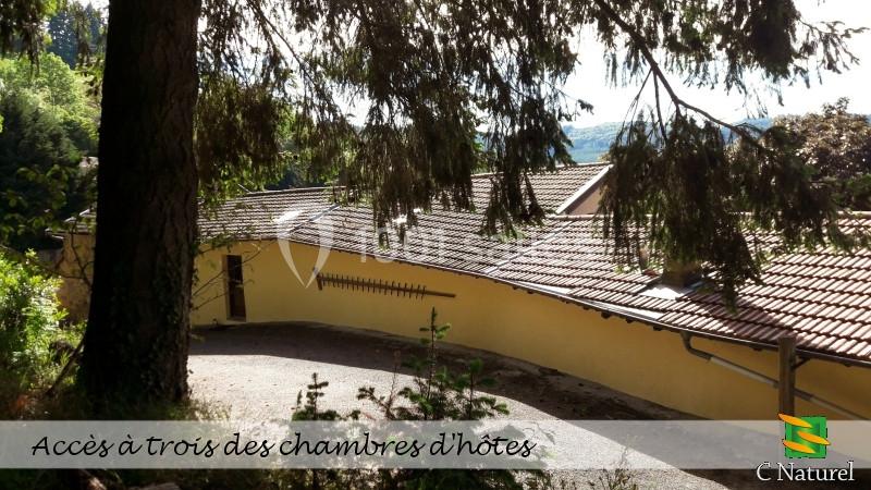 Vue extérieure d'un bâtiment avec toit en tuiles, entouré de végétation, accessible par un chemin pavé.