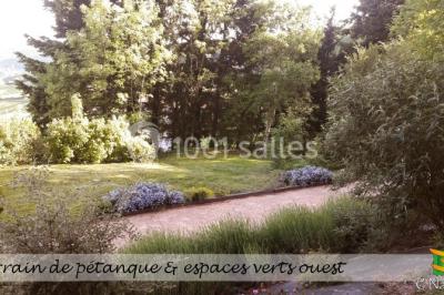 Table en bois décorée pour un repas festif, avec bougies, fleurs et vaisselle, dans une salle aux murs en pierre.