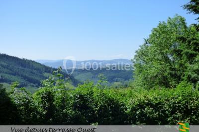 Table en bois décorée pour un repas festif, avec bougies, fleurs et vaisselle, dans une salle aux murs en pierre.