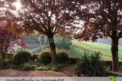 Table en bois décorée pour un repas festif, avec bougies, fleurs et vaisselle, dans une salle aux murs en pierre.