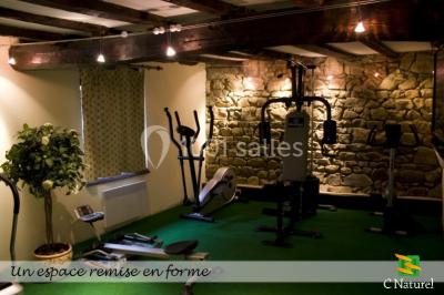 Table en bois décorée pour un repas festif, avec bougies, fleurs et vaisselle, dans une salle aux murs en pierre.