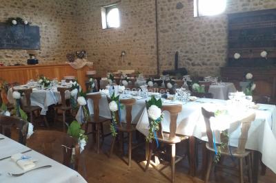 Table en bois décorée pour un repas festif, avec bougies, fleurs et vaisselle, dans une salle aux murs en pierre.