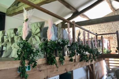 Table en bois décorée pour un repas festif, avec bougies, fleurs et vaisselle, dans une salle aux murs en pierre.