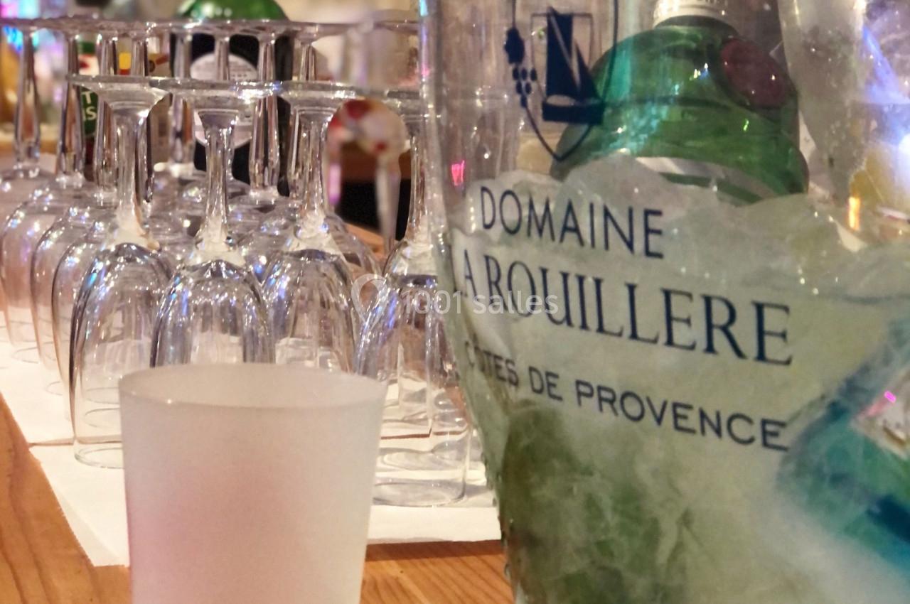 Seau rempli de glace contenant des bouteilles, aligné avec des verres à pied sur une table en bois.