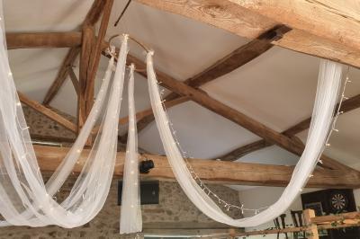 Table en bois décorée pour un repas festif, avec bougies, fleurs et vaisselle, dans une salle aux murs en pierre.