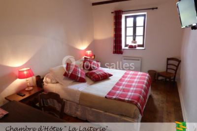 Table en bois décorée pour un repas festif, avec bougies, fleurs et vaisselle, dans une salle aux murs en pierre.