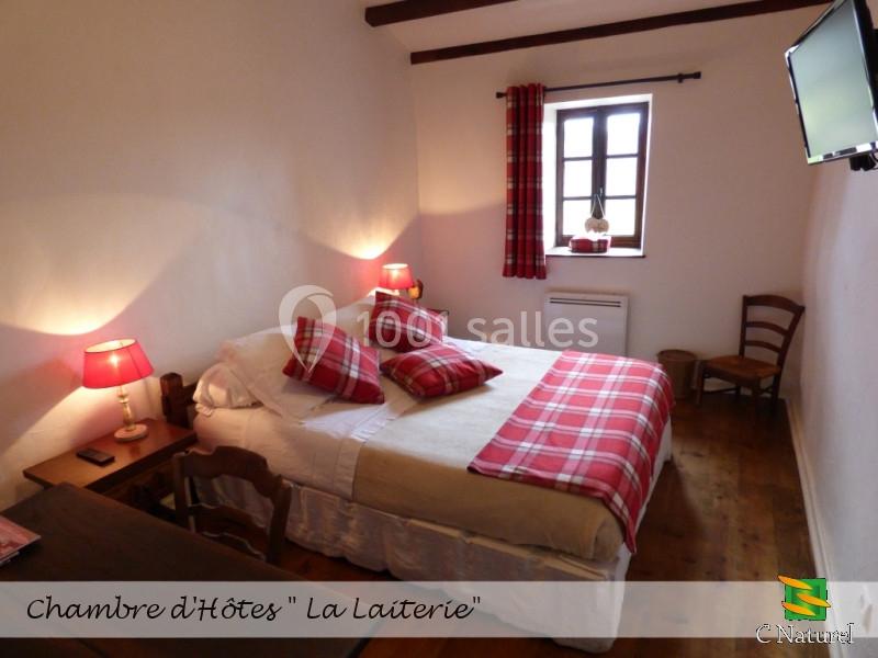 Chambre avec lit double, décorée de tons rouges et blancs, équipée de lampes de chevet et d'une télévision murale.