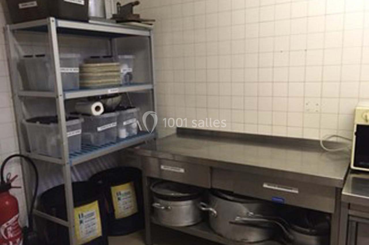 Étagère métallique et plan de travail en acier inoxydable dans une cuisine professionnelle avec ustensiles rangés.