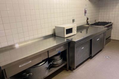 Réfrigérateur professionnel ouvert avec plusieurs étagères métalliques vides dans un environnement de cuisine.