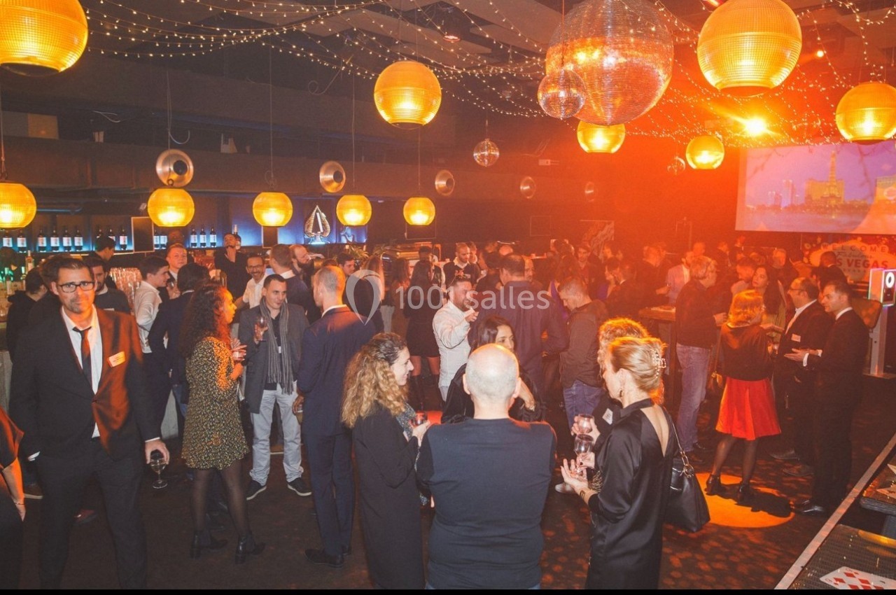 Groupe de personnes socialisant dans une salle décorée de guirlandes lumineuses et de boules disco.