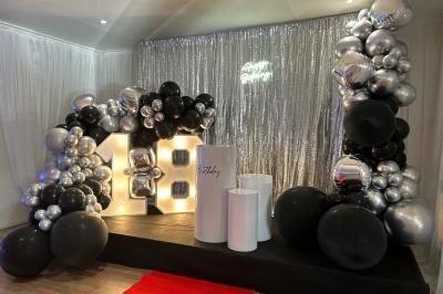 Buffet garni de plats variés sur une longue table blanche, dans une salle décorée avec des ballons suspendus.