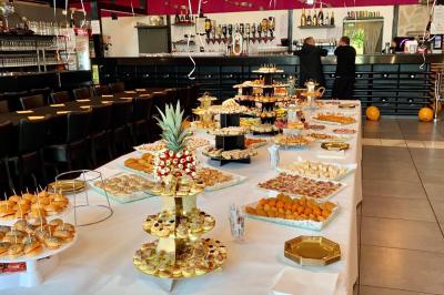 Buffet garni de plats variés sur une longue table blanche, dans une salle décorée avec des ballons suspendus.