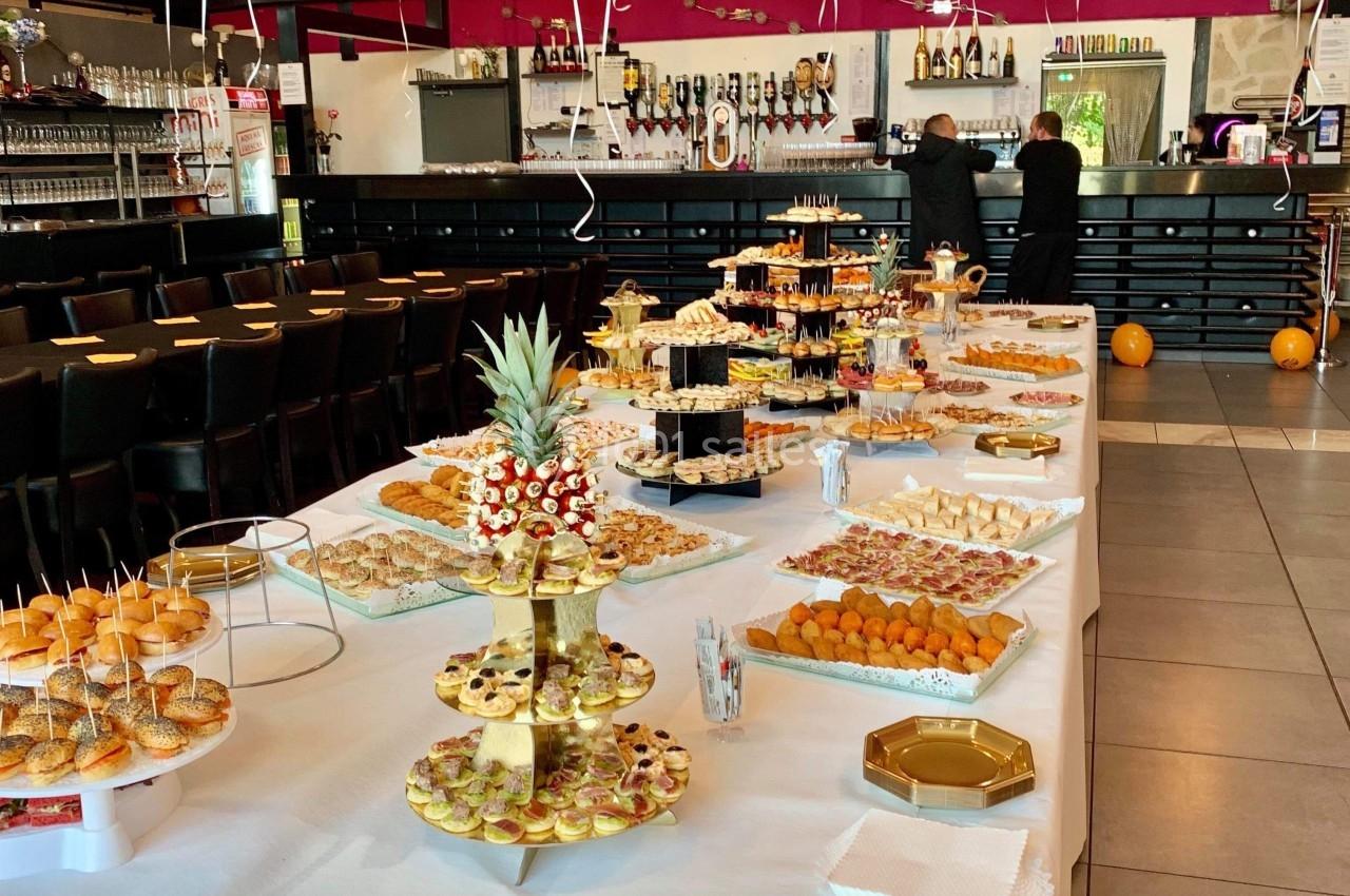 Buffet garni de plats variés sur une longue table blanche, dans une salle décorée avec des ballons suspendus.
