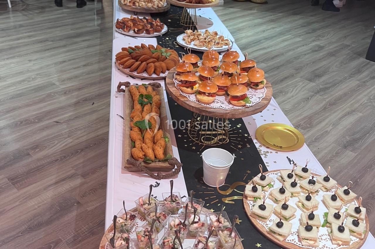 Table garnie de divers amuse-bouches et plats de fête, disposés pour un buffet dans une salle lumineuse.