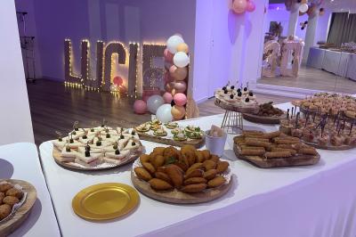 Buffet garni de plats variés sur une longue table blanche, dans une salle décorée avec des ballons suspendus.