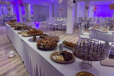 Buffet garni de plats variés sur une longue table blanche, dans une salle décorée avec des ballons suspendus.
