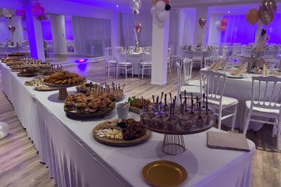 Buffet garni de plats variés sur une longue table blanche, dans une salle décorée avec des ballons suspendus.