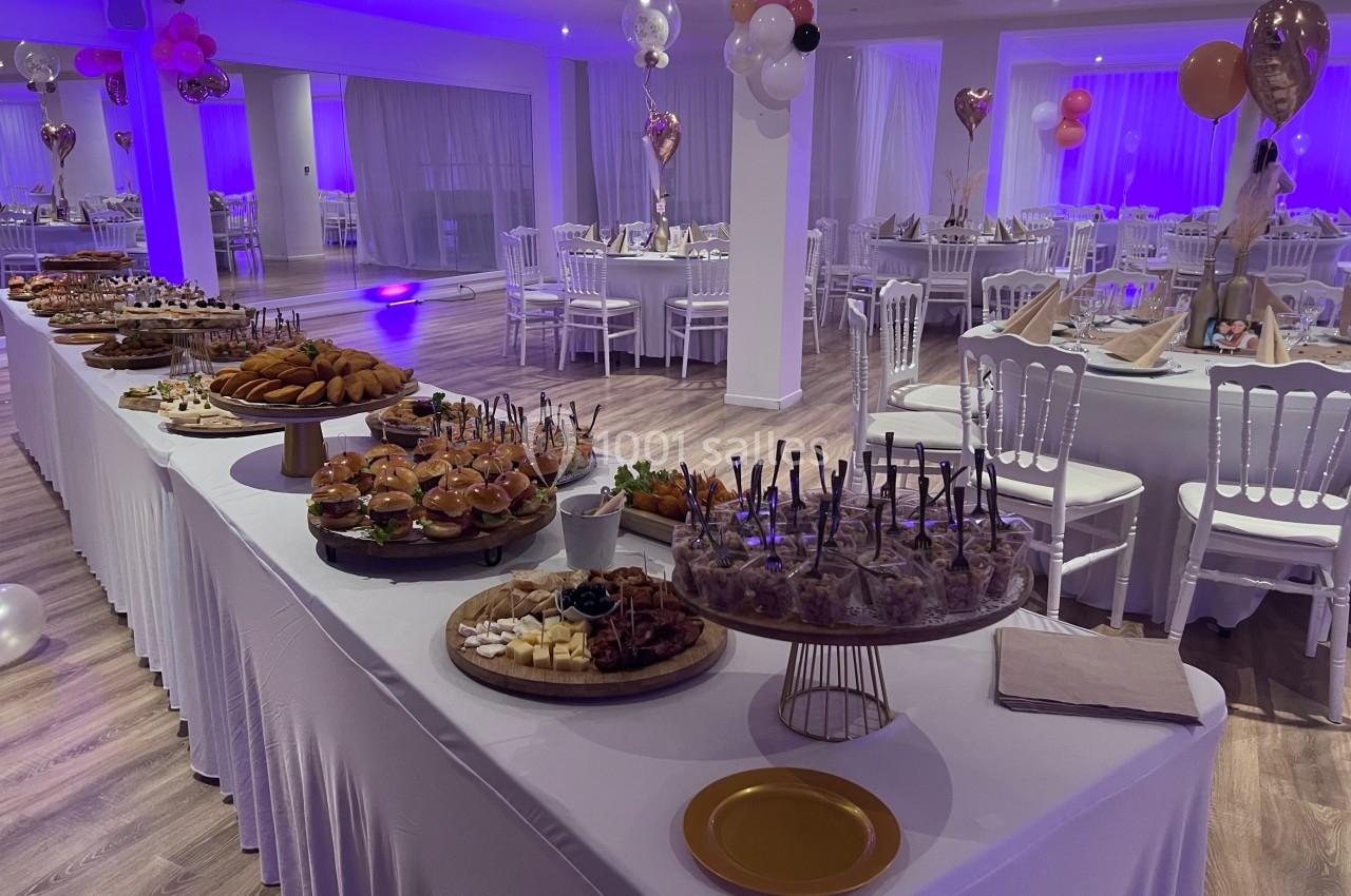 Buffet varié avec plats et desserts sur une longue table, dans une salle décorée pour un événement festif.
