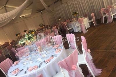 Décoration de salle de réception avec éclairage rose, rideaux, chandeliers et ornements lumineux en forme de cœur.