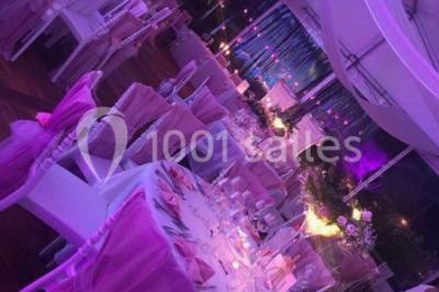 Décoration de salle de réception avec éclairage rose, rideaux, chandeliers et ornements lumineux en forme de cœur.