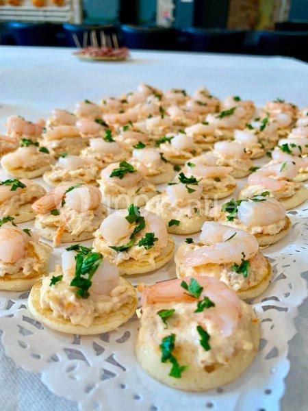 Plateau de canapés garnis de crevettes, mousse salée et persil, disposés sur une nappe blanche.