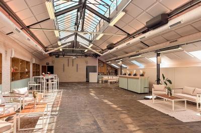 Salon chaleureux avec canapé jaune, fauteuils en rotin, table basse ronde, lampes et décorations murales abstraites.