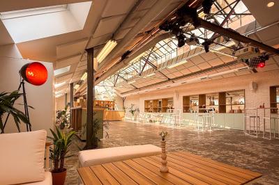 Salon chaleureux avec canapé jaune, fauteuils en rotin, table basse ronde, lampes et décorations murales abstraites.