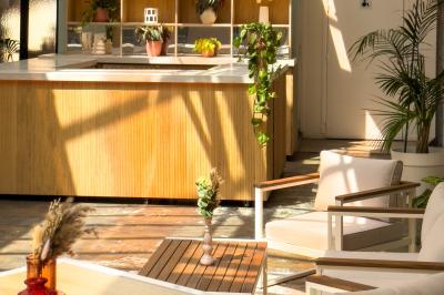 Salon chaleureux avec canapé jaune, fauteuils en rotin, table basse ronde, lampes et décorations murales abstraites.