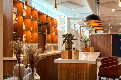 Salon chaleureux avec canapé jaune, fauteuils en rotin, table basse ronde, lampes et décorations murales abstraites.