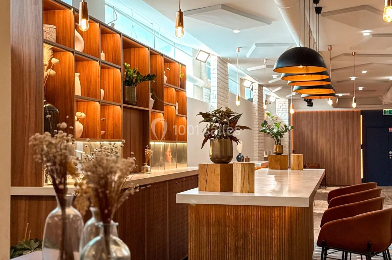 Intérieur d'un café moderne avec comptoirs en bois, étagères éclairées, suspensions design et chaises hautes.