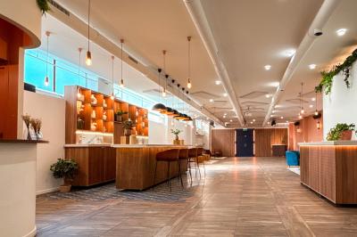 Salon chaleureux avec canapé jaune, fauteuils en rotin, table basse ronde, lampes et décorations murales abstraites.