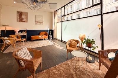 Salon chaleureux avec canapé jaune, fauteuils en rotin, table basse ronde, lampes et décorations murales abstraites.