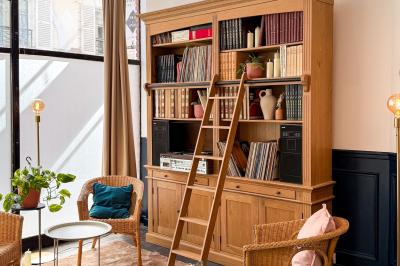 Salon chaleureux avec canapé jaune, fauteuils en rotin, table basse ronde, lampes et décorations murales abstraites.