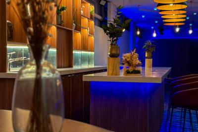 Salon chaleureux avec canapé jaune, fauteuils en rotin, table basse ronde, lampes et décorations murales abstraites.