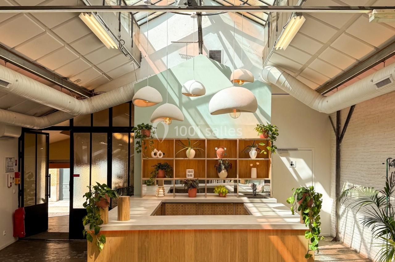 Cuisine moderne avec un îlot central en bois, éclairée par une verrière et des suspensions lumineuses.