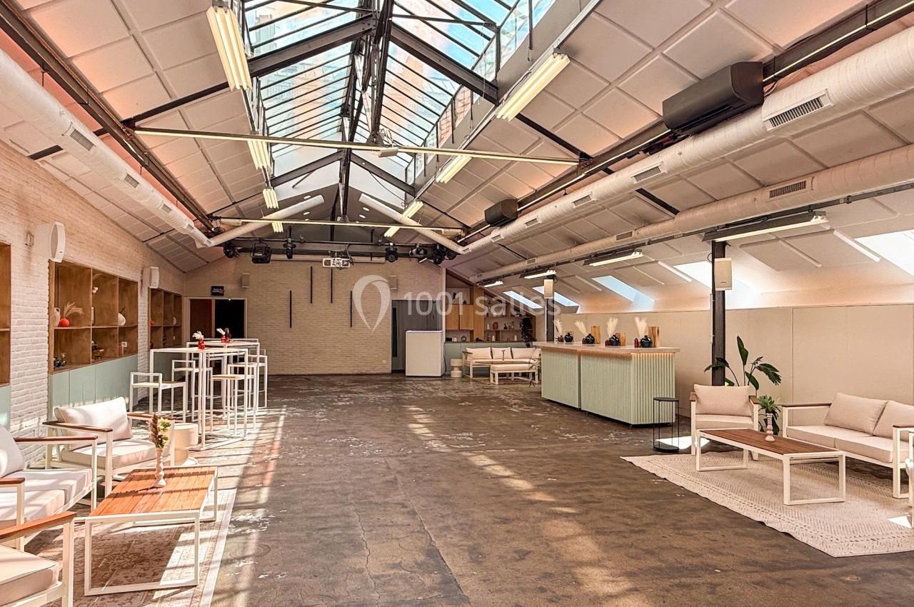 Espace lumineux avec verrière, mobilier moderne et coin salon, dans un intérieur de style industriel.