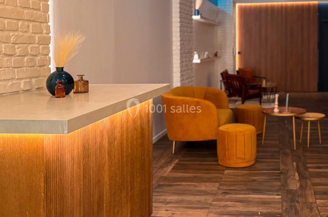 Espace intérieur chaleureux avec mobilier en velours orange, comptoir en bois clair et éclairage tamisé.