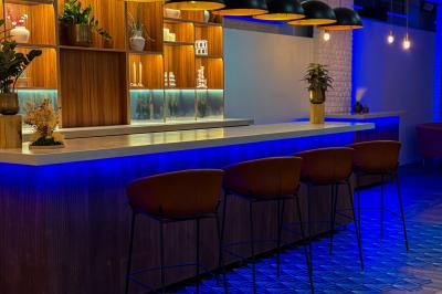 Salon cosy avec canapé jaune, fauteuils en rotin, table basse ronde, lampes et décorations murales dans une ambiance…