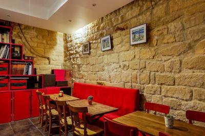 Bar avec comptoir rouge éclairé, tabourets hauts, murs en pierre et briques, décorations murales et étagères avec bouteilles.