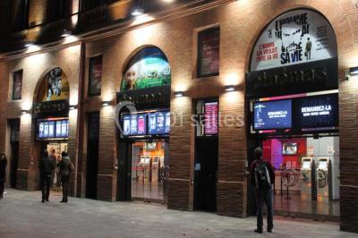Espace intérieur moderne avec éclairage coloré, affiches promotionnelles et signalétique pour un événement.