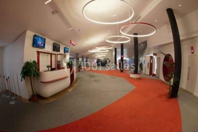 Espace intérieur moderne avec éclairage coloré, affiches promotionnelles et signalétique pour un événement.