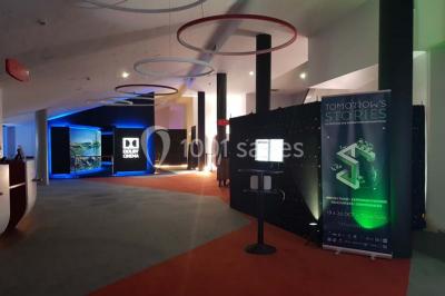 Espace intérieur moderne avec éclairage coloré, affiches promotionnelles et signalétique pour un événement.