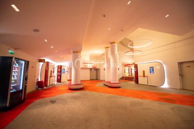 Espace intérieur moderne avec éclairage coloré, affiches promotionnelles et signalétique pour un événement.