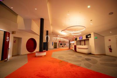 Espace intérieur moderne avec éclairage coloré, affiches promotionnelles et signalétique pour un événement.