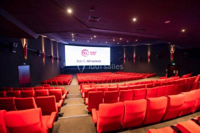 Espace intérieur moderne avec éclairage coloré, affiches promotionnelles et signalétique pour un événement.