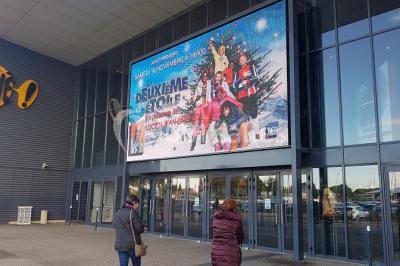Salle vide avec moquette sombre, grande baie vitrée et structures métalliques visibles en arrière-plan.