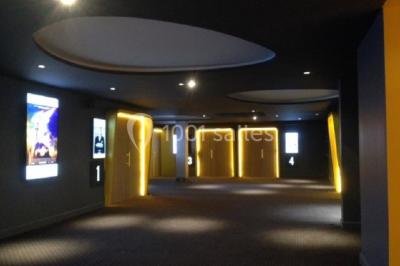 Salle vide avec moquette sombre, grande baie vitrée et structures métalliques visibles en arrière-plan.